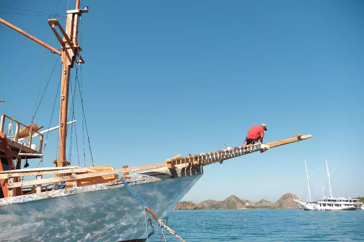 A boat builder working on the bowsprit of a phinisi under construction in Labuan Bajo